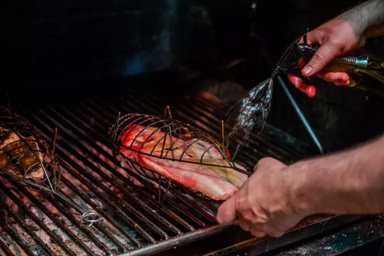 Virrey en la parrilla a la brasa en su besuguera siendo aliñada